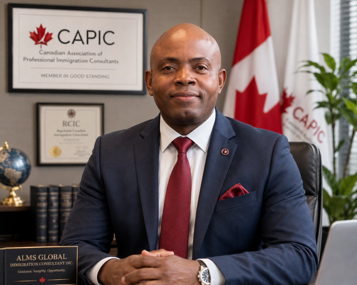 Aloysius Adimaulor, Regulated Canadian Immigration Consultant, seated at his desk